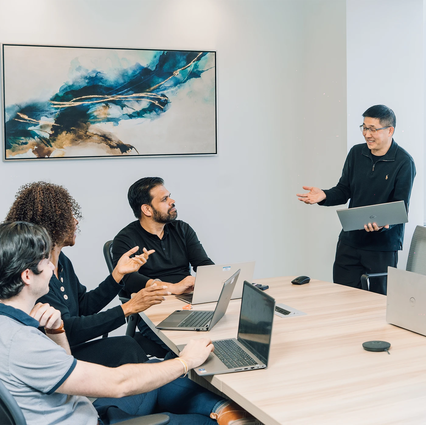 Precise team members discuss projects around a conference room table